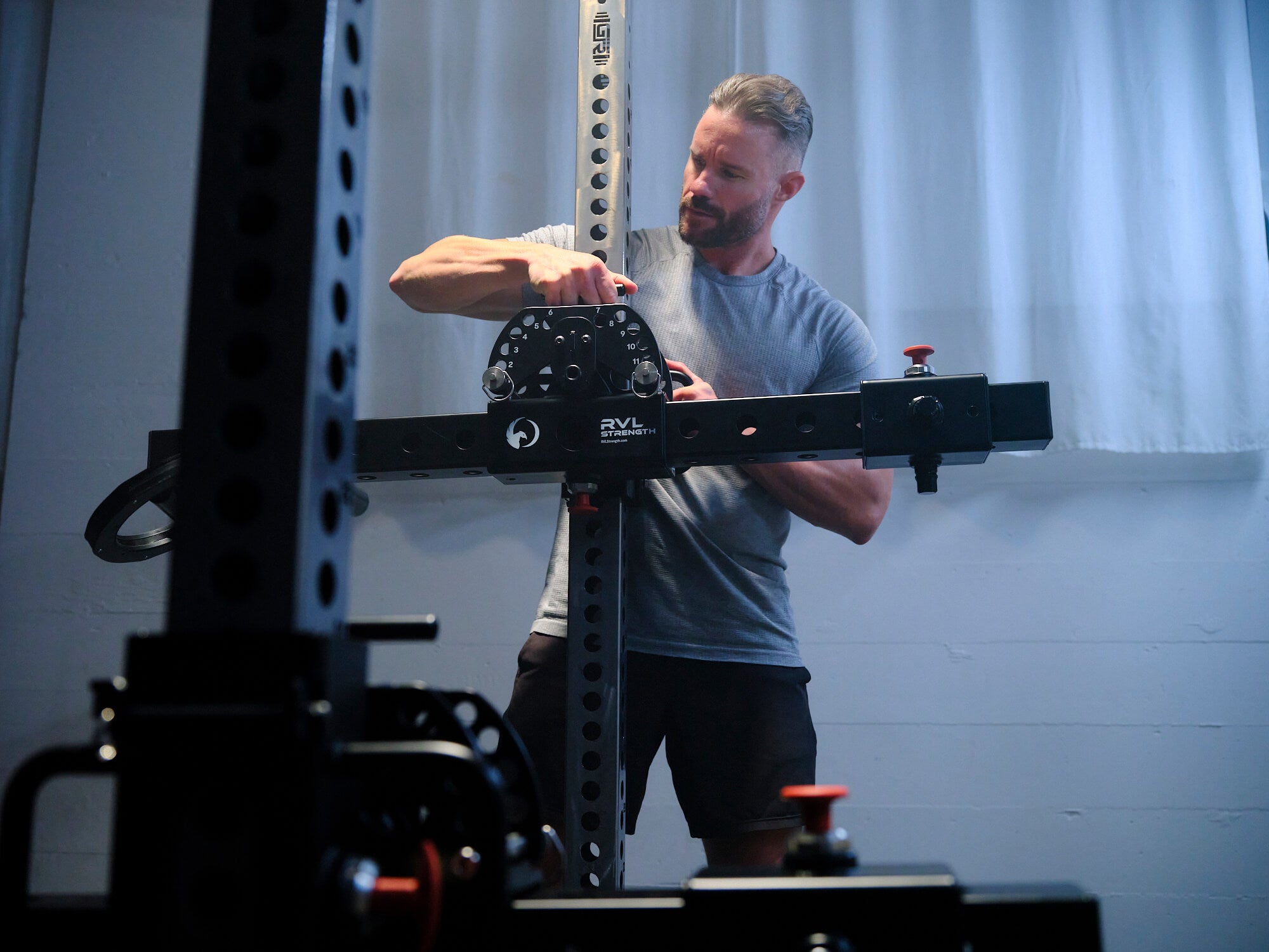 Man adjusting the RVL Wings height setting on the power rack upright 